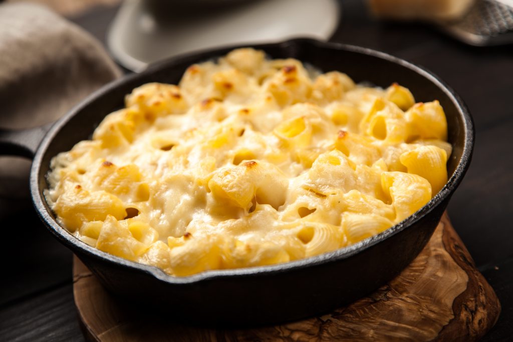mac and cheese in a small pan on a wooden board 