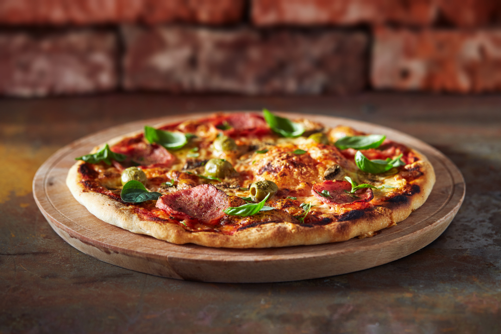 A wood fired pizza on a wooden board in an article about restaurant in Knoxville 