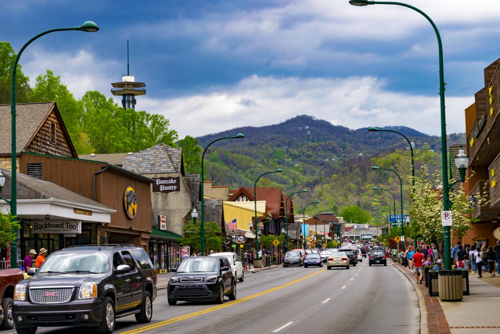 Downtown street where you can eat pancakes for breakfast in Gatlinburg, with a tree-covered mountain in the background.