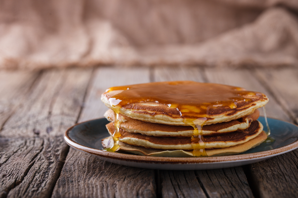 A closeup of a small stack of pancakes with syrup running down the sides, one of the most popular foods for breakfast in Gatlinburg.