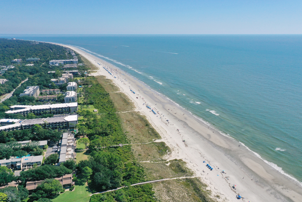 Areial view of Hilton Head beach showing hotels in the trres, a large expanse of beach and beautiful blue water. One of the beaches in Savannah.  