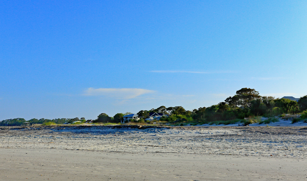 South beach at Tybee Island a large expanse of sand with trees and houses in the background. 