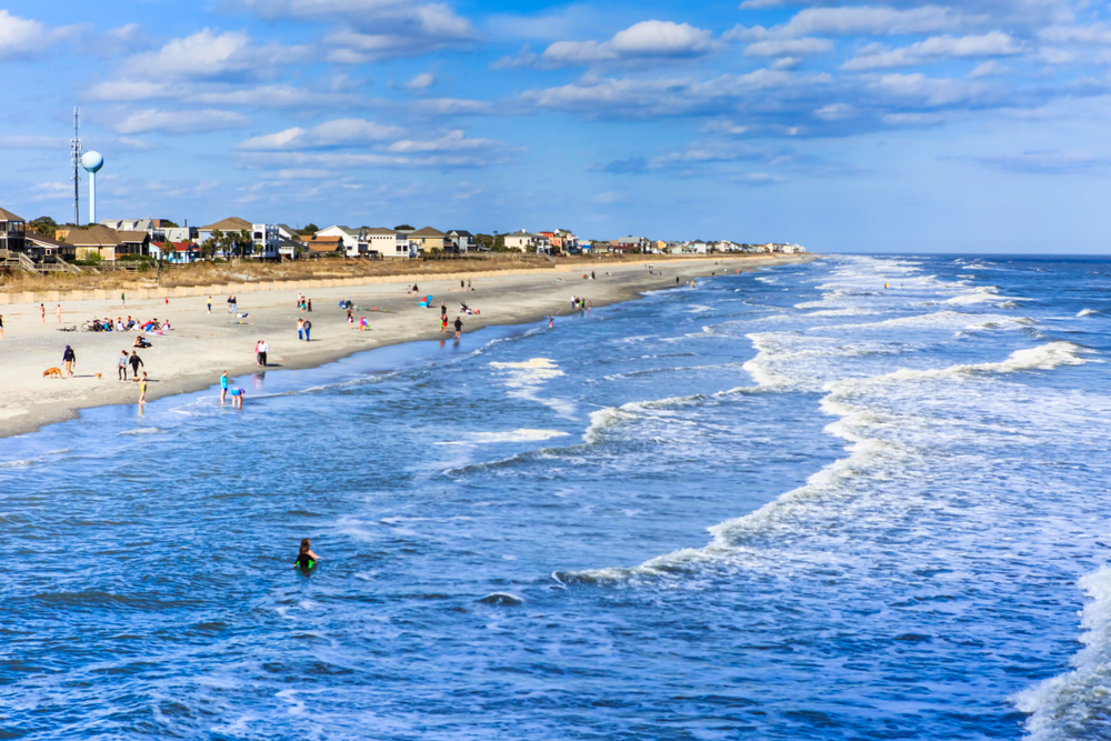 Beachgoers enjoying the sun and water on a beautiful day with blue skies!