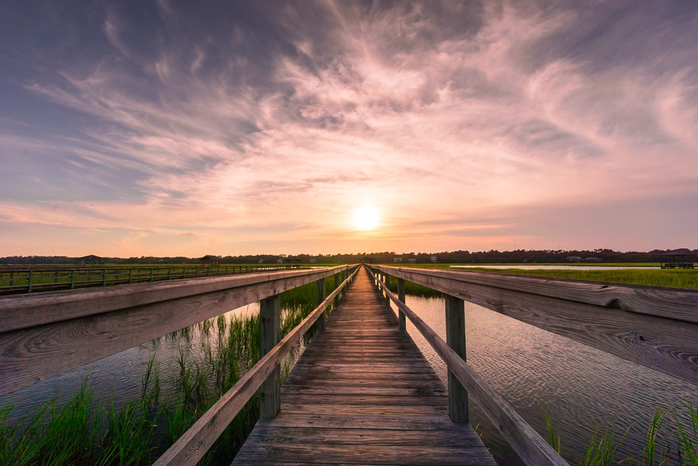 Sunset over a boardwalk through marshlands at one of the beaches in South Carolina.