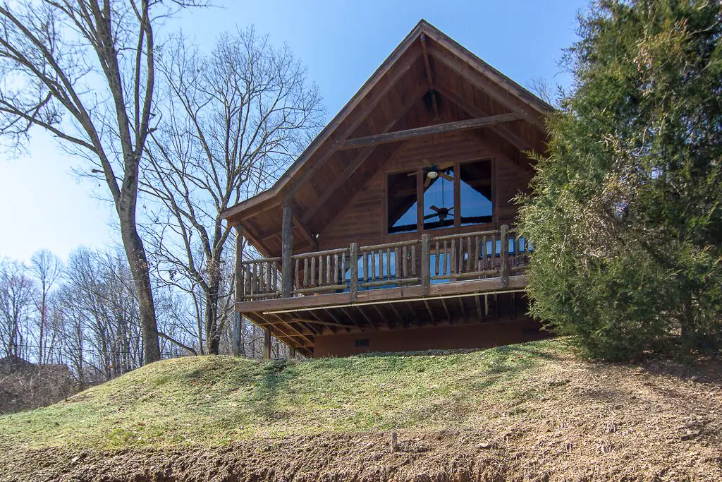 A log cabin with a porch overlooking the view below in an article about cabins in Tennessee.