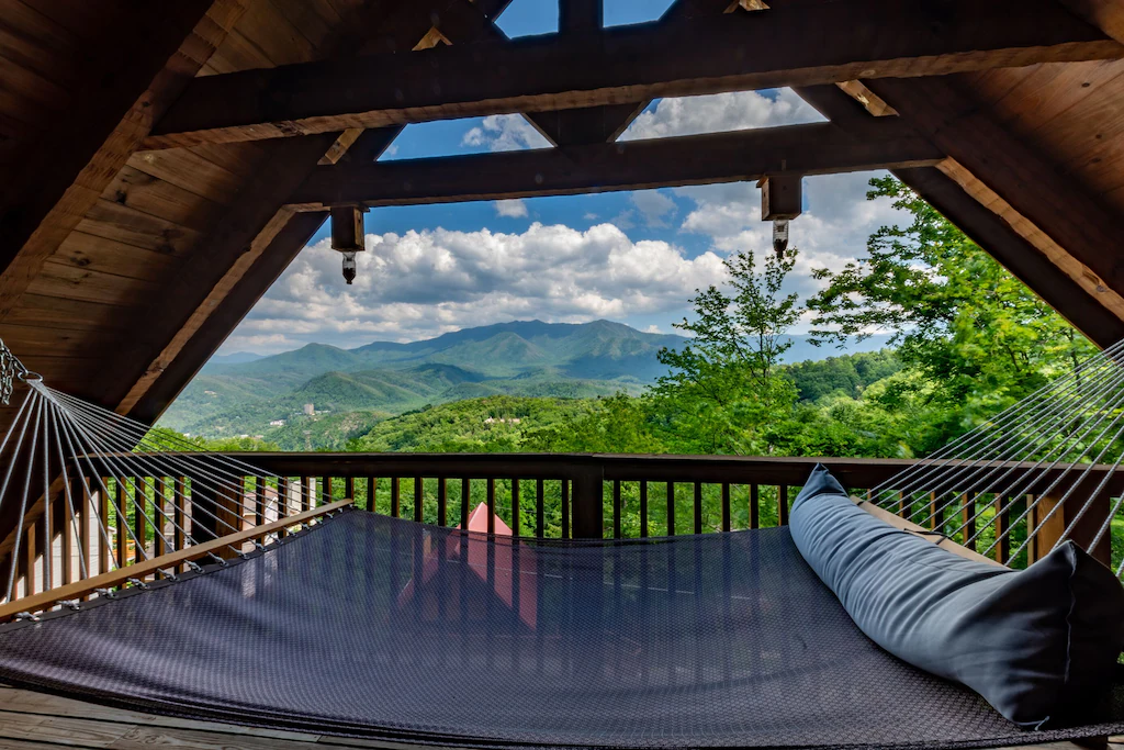 Increadible view of mountains from a hammock in a log cabin . 