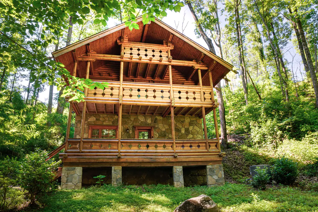 A three story log cabin with an ornate balcony overlooking the view below. 