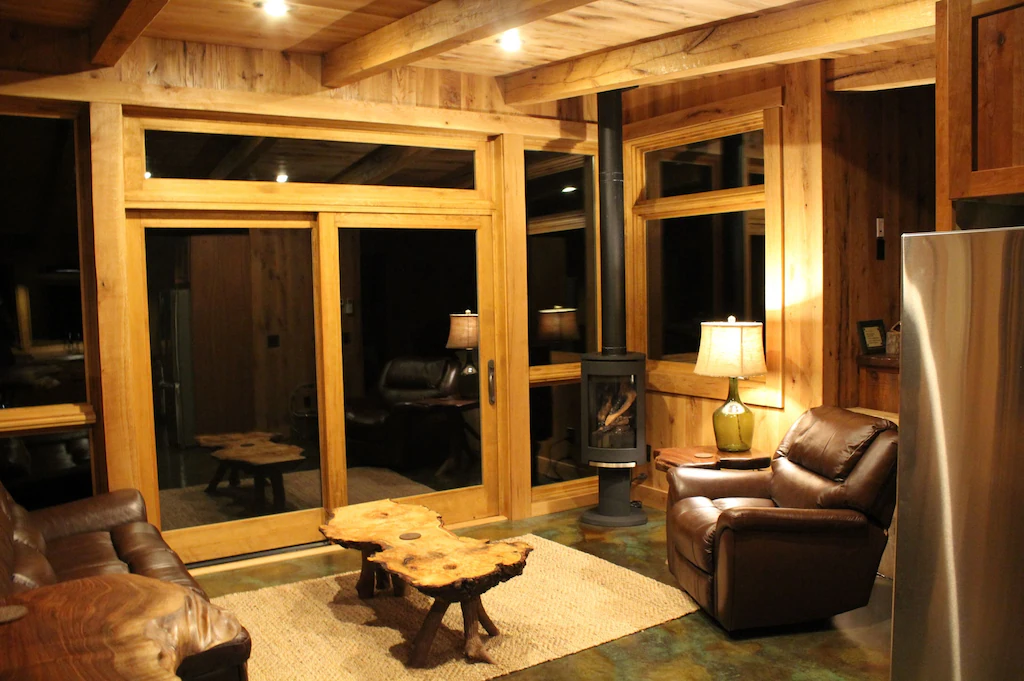inside of modern cabin with recliner, wood burning stover, and log coffee table