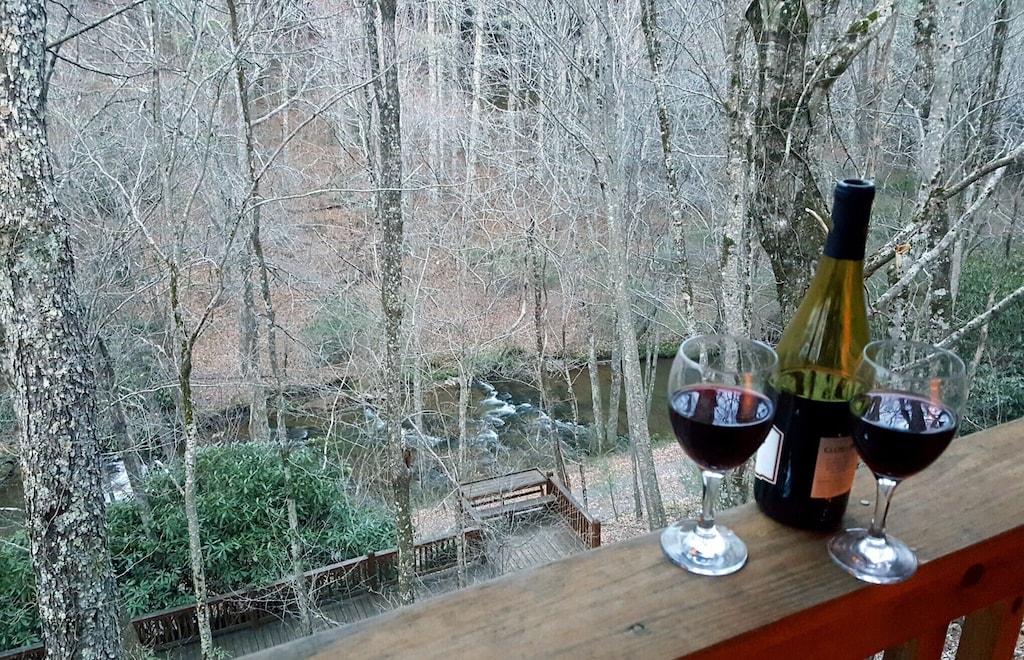 porch railing with wine glasses looking down on creek below
