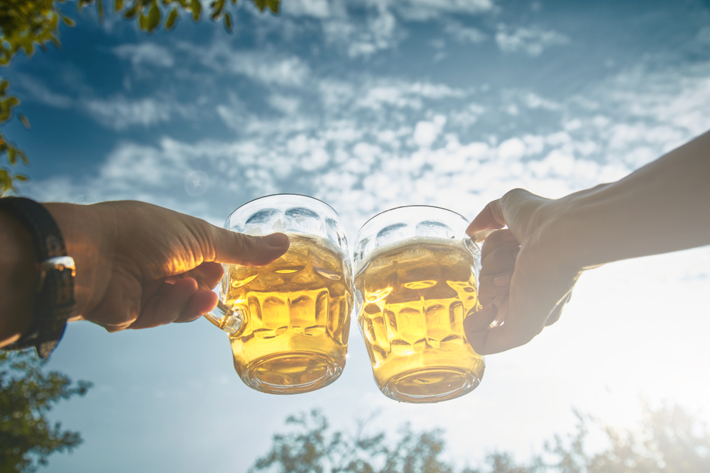 A couple cheers two beers in the air while enjoying the outdoors during a date night in Atlanta.