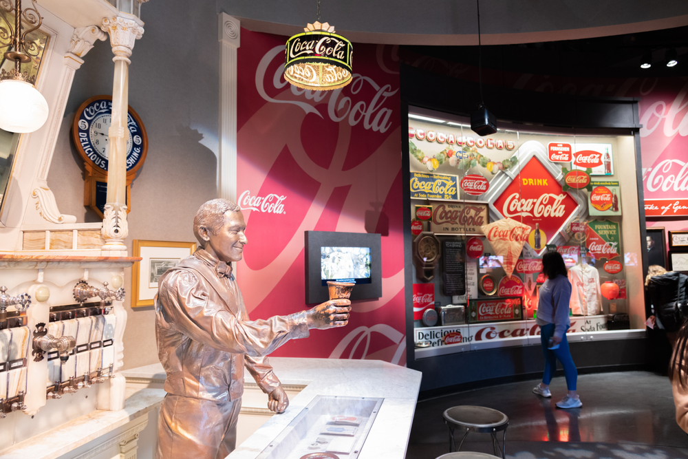 A woman stands in front of displays at the World of Coca-Cola, which is a perfect place for date night in Atlanta.