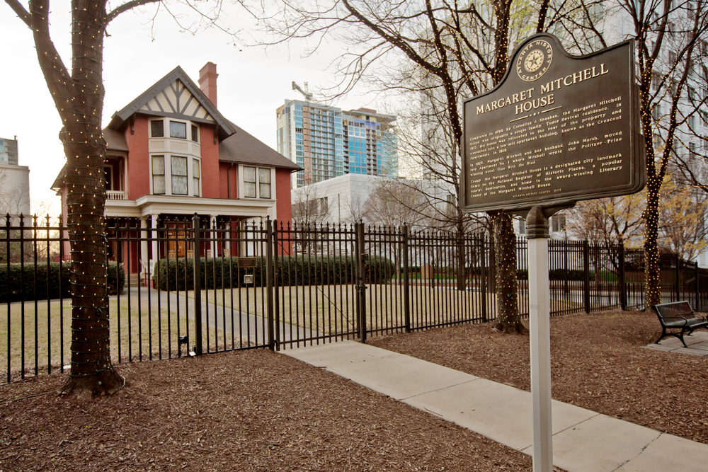 The image is of the Margaret Mitchell House, which is a red building surrounded by a fence. Locals and tourists love to come here for a date night in Atlanta. 