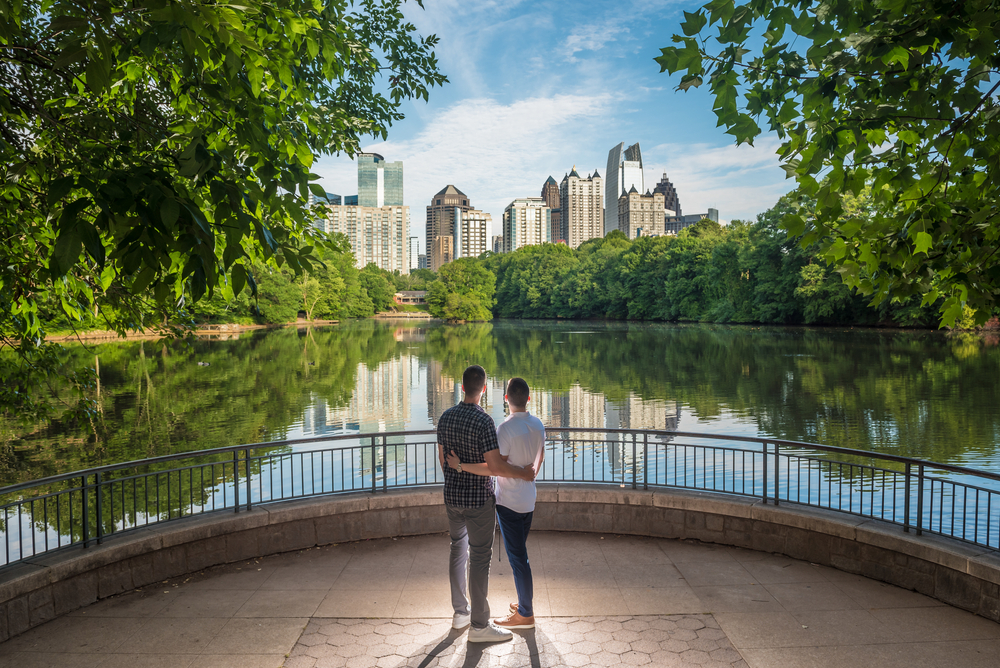 A couple overlooks the city and the lake and the nature of a park, enjoying a date night in Atlanta.