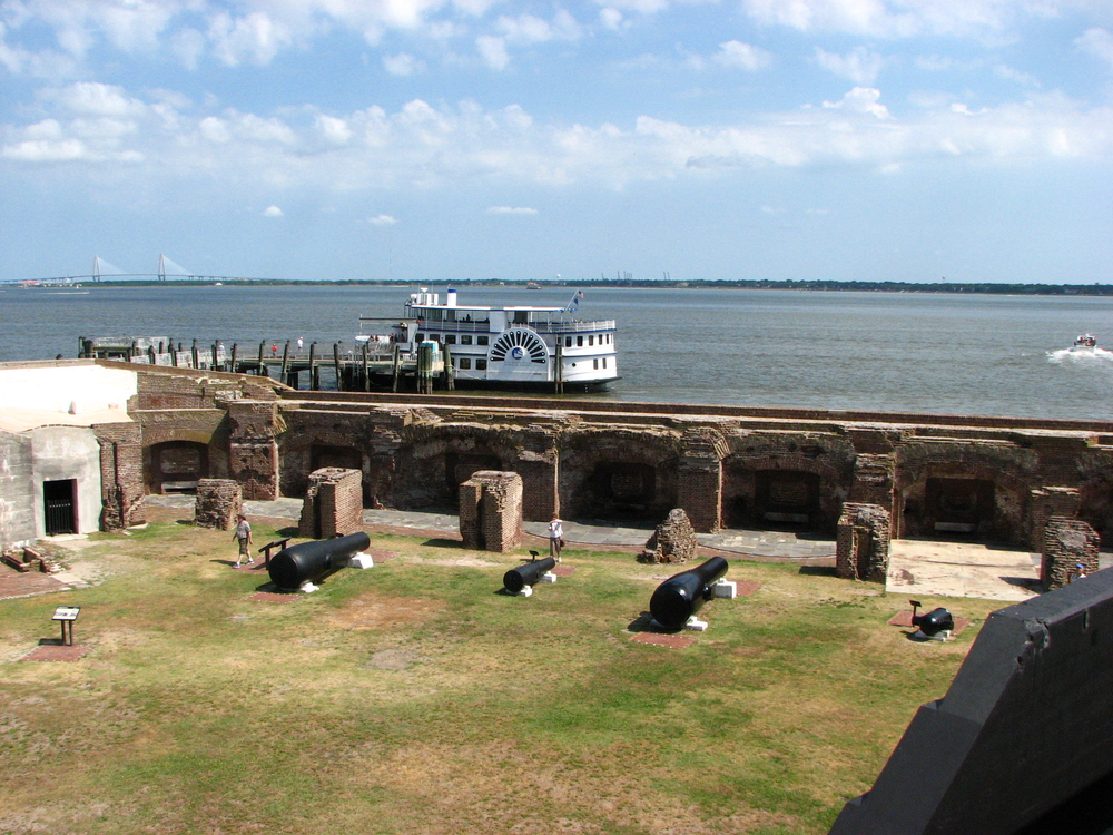 Fort Sumter with guns visible and a steamboat docked in the water. 