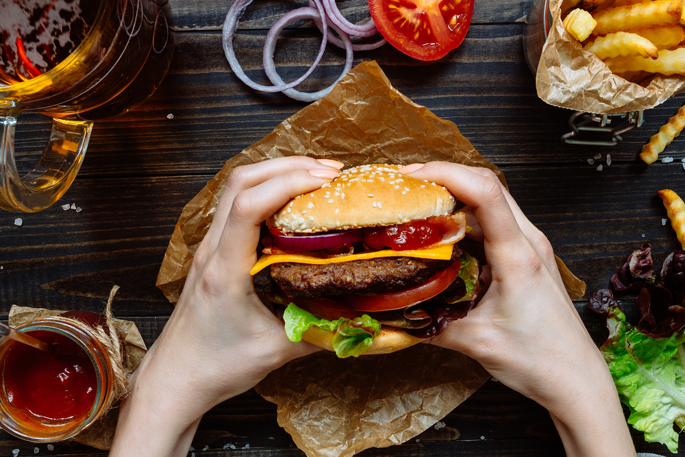 Girl holding a burger in front of her with some beer and ketchup off to the side in an article about restaurants in Pigeon Forge