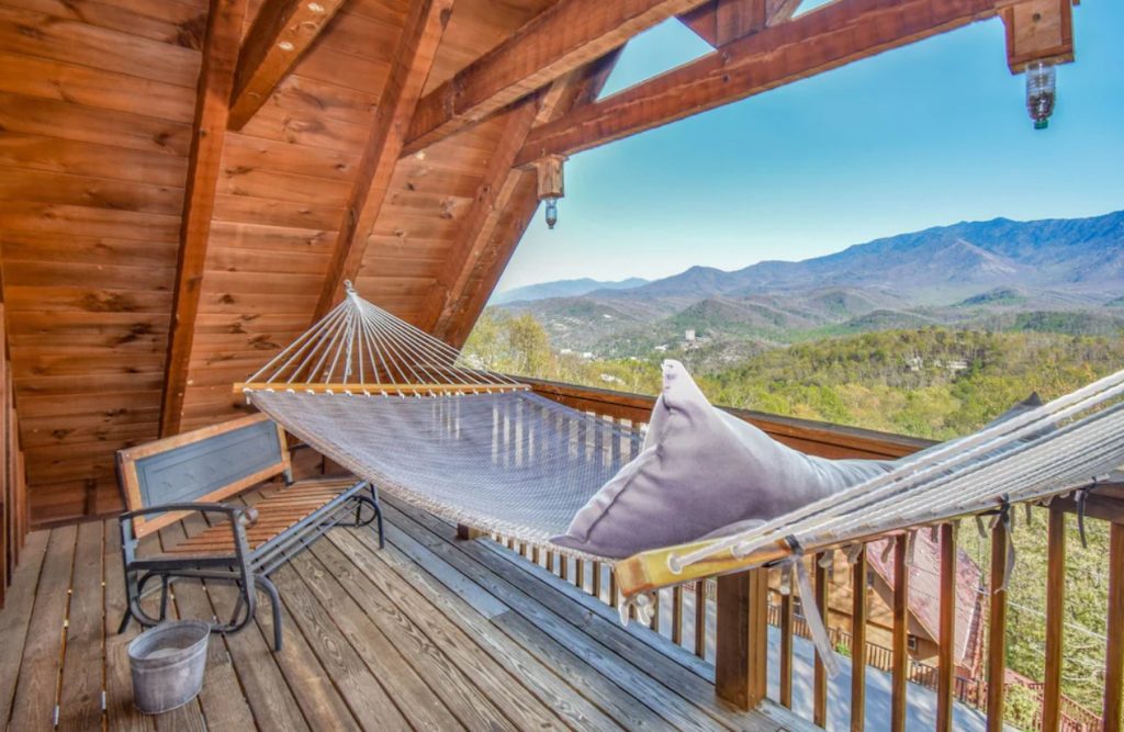 A deck in the peak of a cabin that overlooks Gatlinburg and the mountains. The deck has a hammock and a bench. It's one of the best cabins in Gatlinburg. 