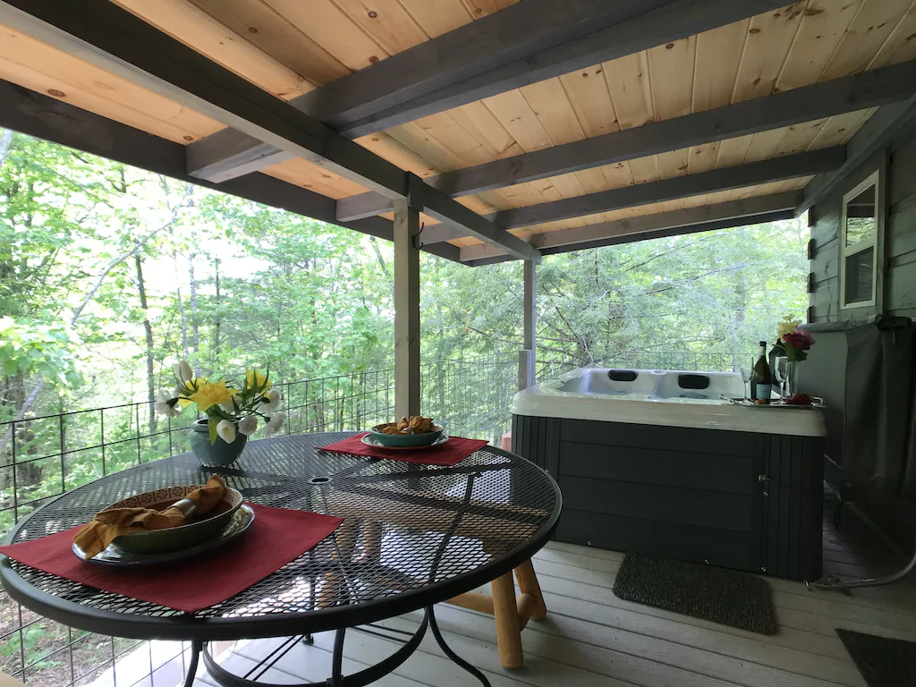 Large deck with a table and chairs and a hot tub overlooking the trees.  This is one of the treehouses in Tennessee that you won't want to miss. 