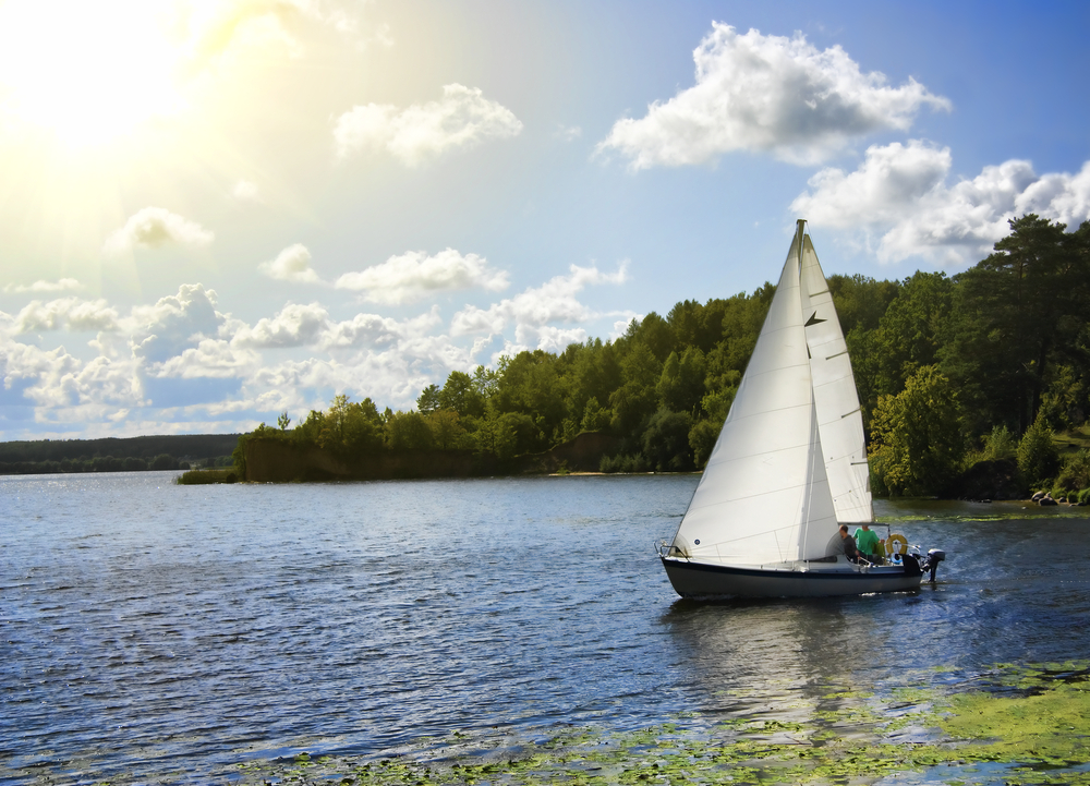 A sailboat moves across calm lake water. Amongst other things, Arkabutla Lake is known for its sailing scene.