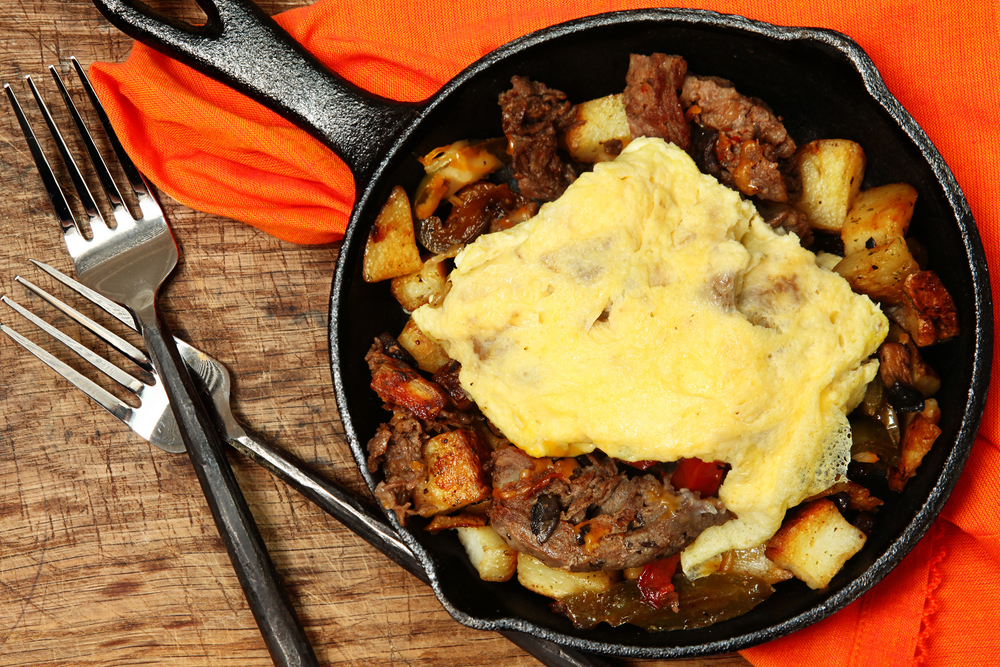 On top of a bright orange napkin sits a breakfast skillet filled with meat, potatoes, and scrambled egg, like those served at Flapjack's Pancake House for breakfast in Pigeon Forge.