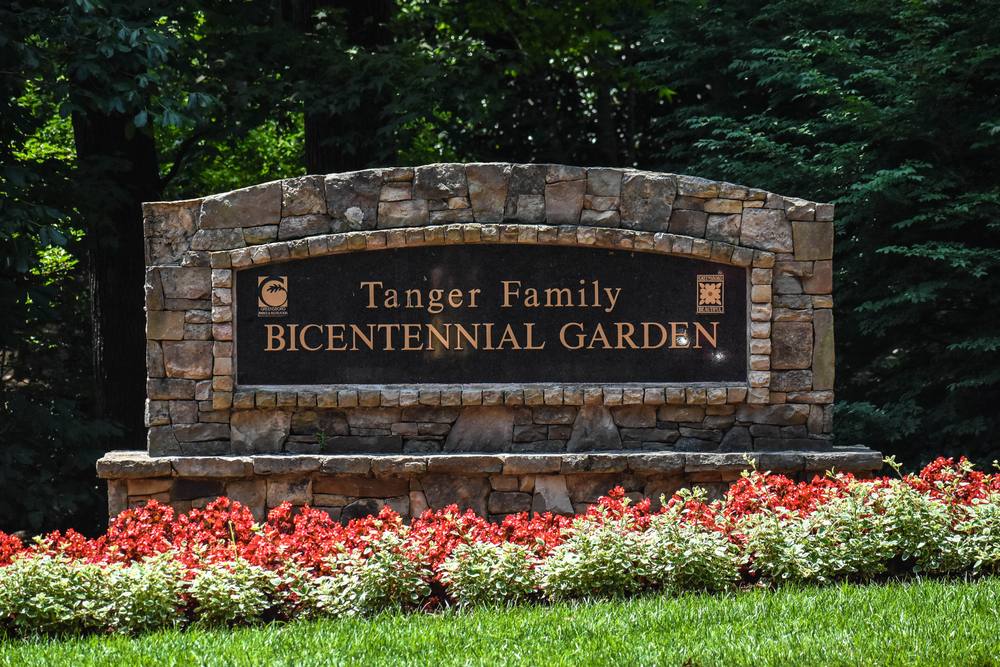 One of the most relaxing things to do in Greensboro is to visit Tanger Family Bicentennial Garden. In this photo the sign is shown with red flowers along the bottom.