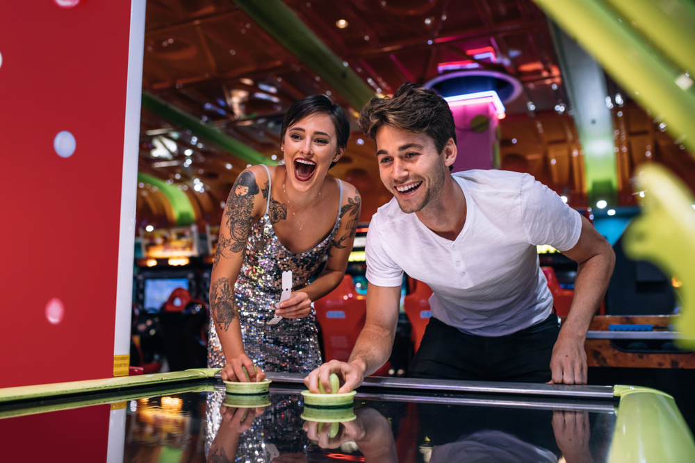 Couple playing air hockey at an arcade at one of the fun amusement parks in Georgia. 