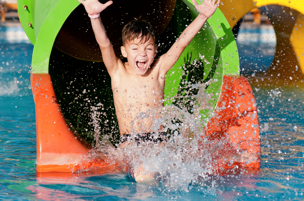 Boy splashing into water at the end of a water slide at one of the Georgia theme parks. 