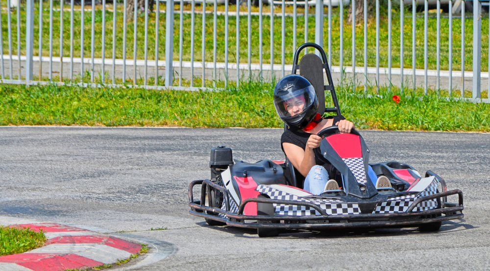 Woman driving a go-kart around a tight corner on a go-kart track at one of the amusement parks in Georgia. 
