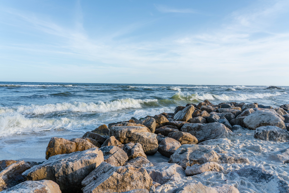 photo of sandy beach and rocks on waters edge