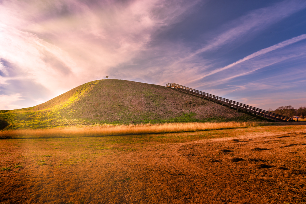 A large mound with steps up the side of it. The sun is casting rays on the mound. It is one of the best hidden gems in Georgia. 