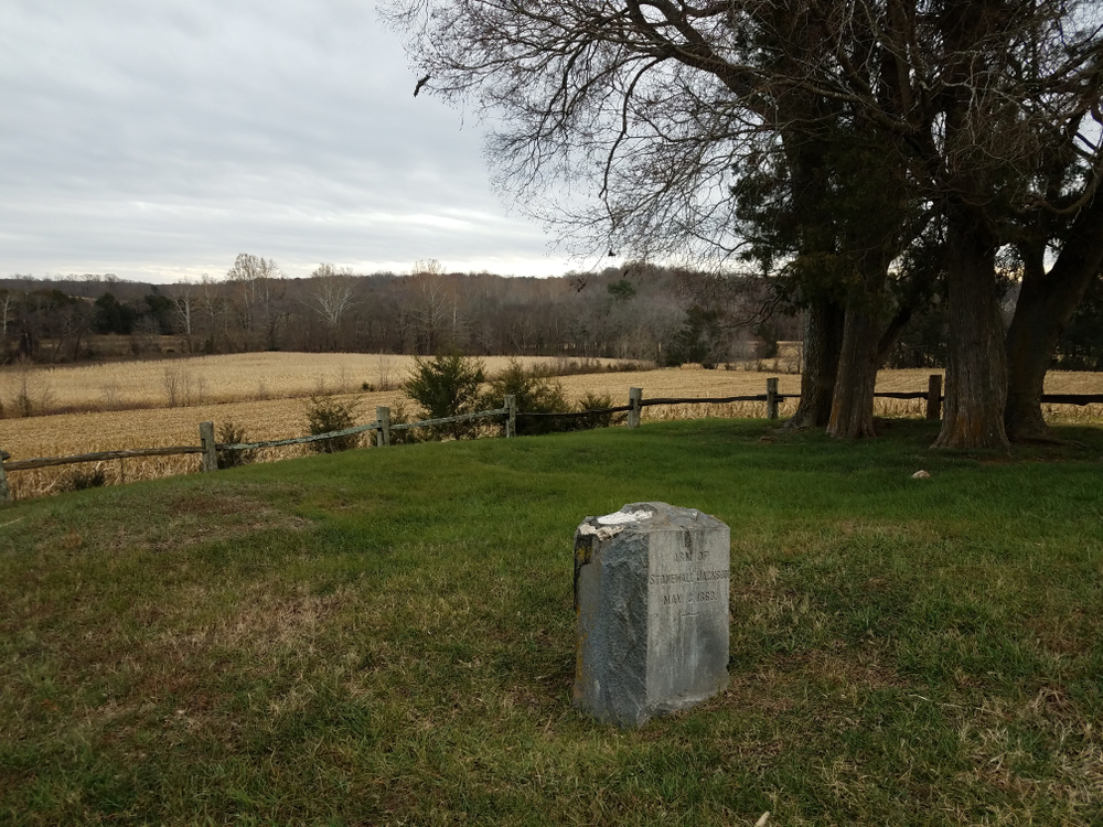 A small stone marker that marks the spot where General Stonewall Jackson's arm is buried. It's in the middle of a grassy field on a farm. 