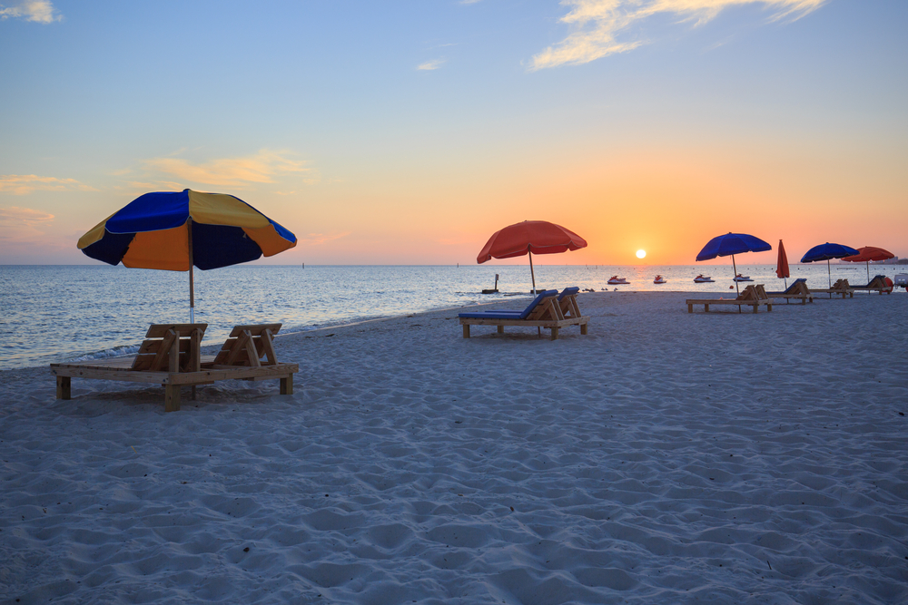 Photo of umbrellas and chairs on the beach during a Biloxi Beach sunset.