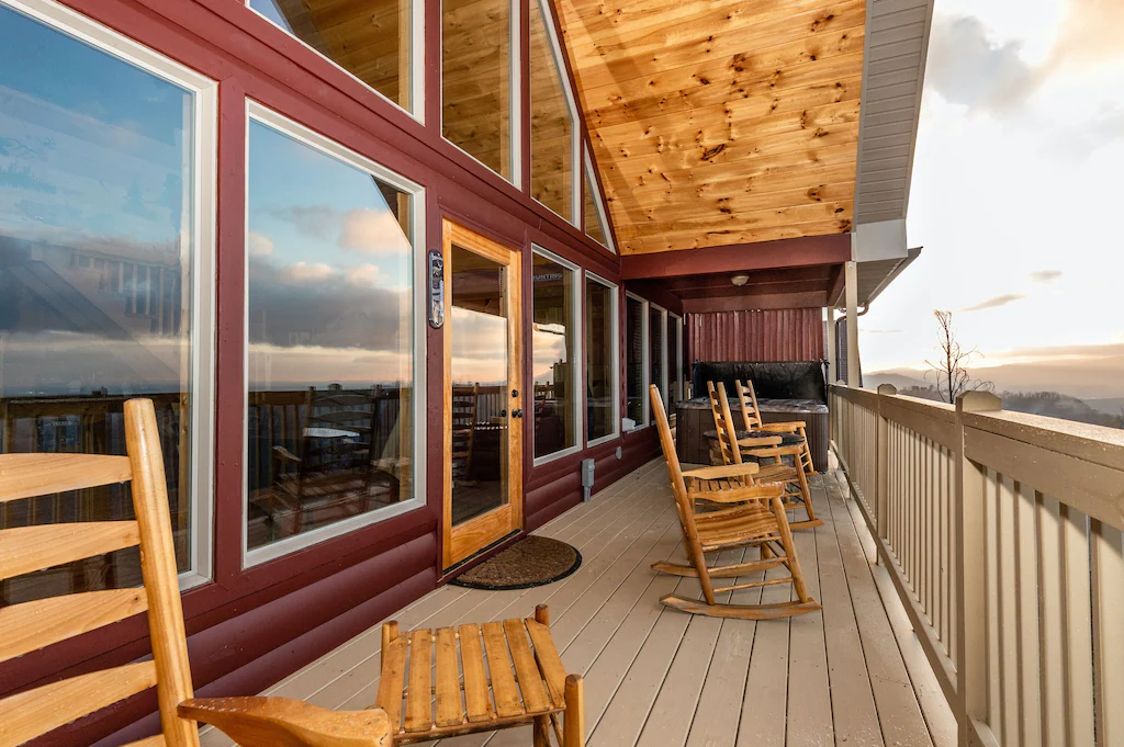 large deck of cabin with mountain views. rocking chairs and hot tub on the deck 
