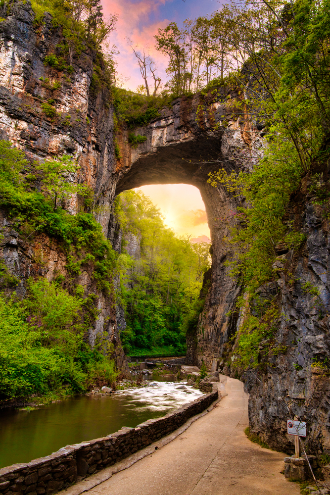 The natural bridge in Virginia which has a river under it and is surrounded by trees. One of the best hidden gems in Virginia. 