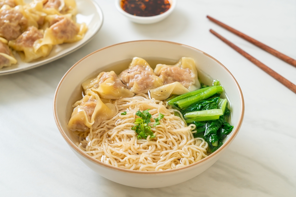 A homemade noodle soup with noodles, dumplings, and fresh veggies in a broth