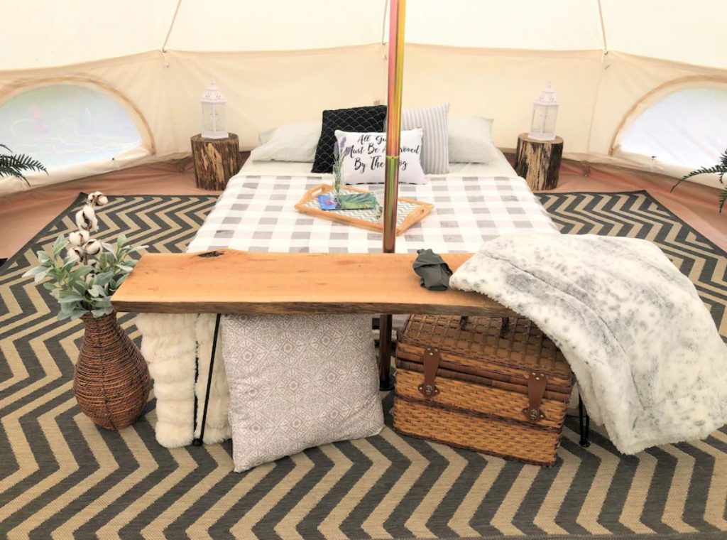 The interior of a luxury tent for glamping in North Carolina. There is a queen sized bed, blankets, a rug, and more spread out in the tent. Its a great spot for glamping in North Carolina.