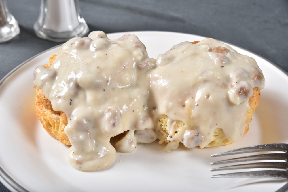 Two biscuits covered in gravy sit on a white plate, one of the most popular meals for breakfast in Charleston.