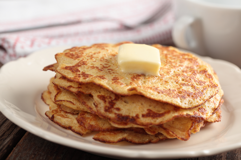 A small stack of cornmeal pancakes topped with butter, similar to those served at Millers All Day for breakfast in Charleston.