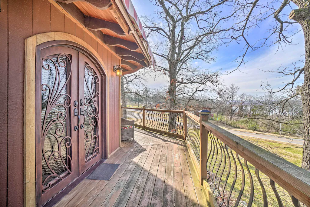 A treehouse with an ornate carved door overlooking frass and a river. 