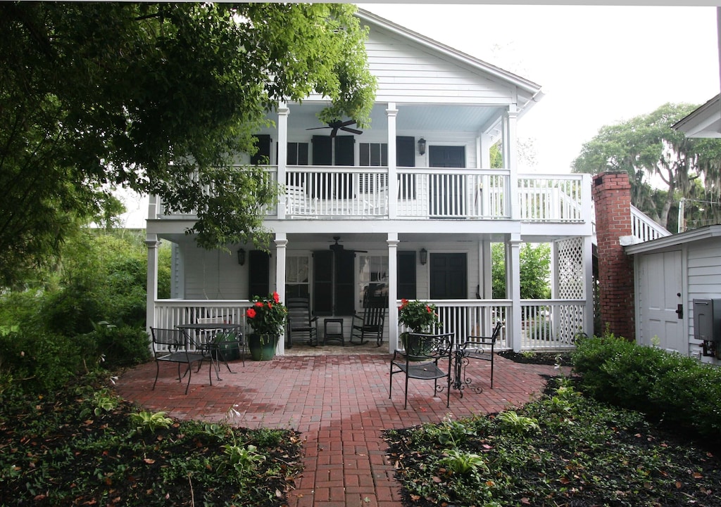 View of the old growth oak trees and whitewashed carriage house with two levels of wrap around porches 