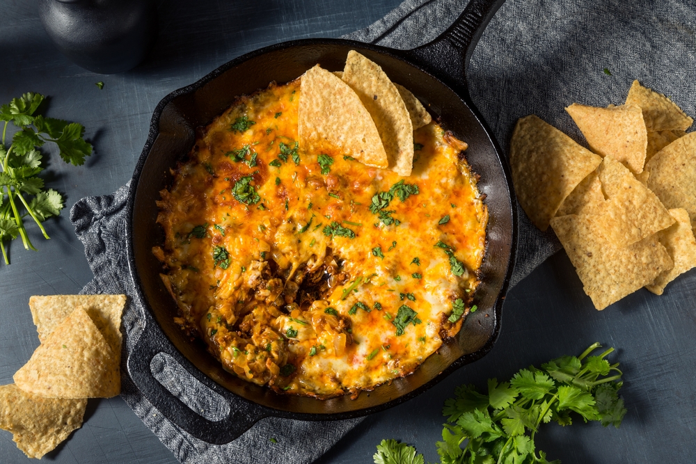 Chips sit in the corner of a queso dip in a skillet: shareables like these are popular amongst  some of the best restaurants in San Antoni