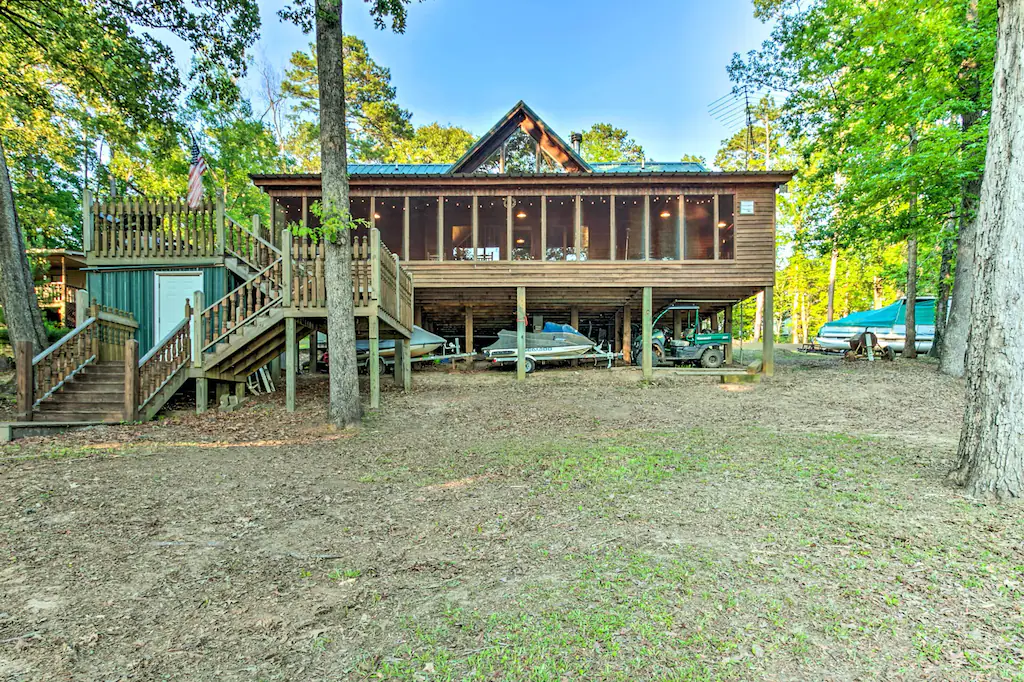 Great cabin with a green roof and large porch space and cool winding staircase down to the ground, a great option for cabin rentals in Louisiana!
