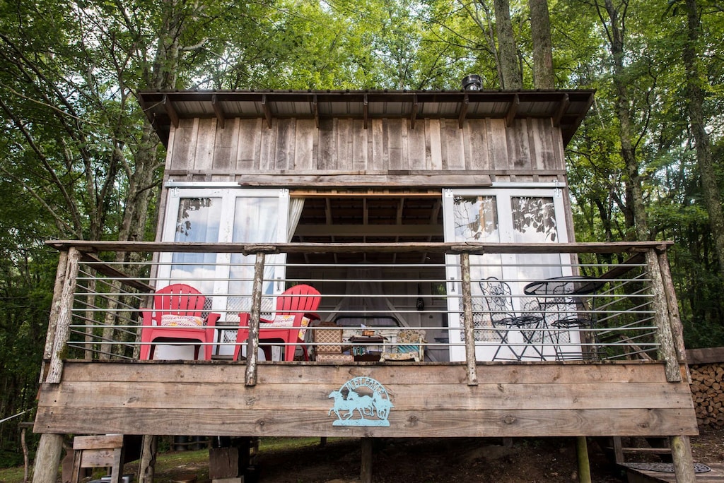wooden structure with a porch and red Adirondack chairs at one of the sites for glamping in tennessee 
