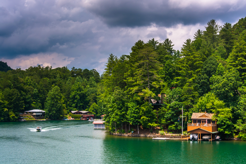 green trees and cloudy skies but strong sun rays over the waterfront properties on lakes in georgia