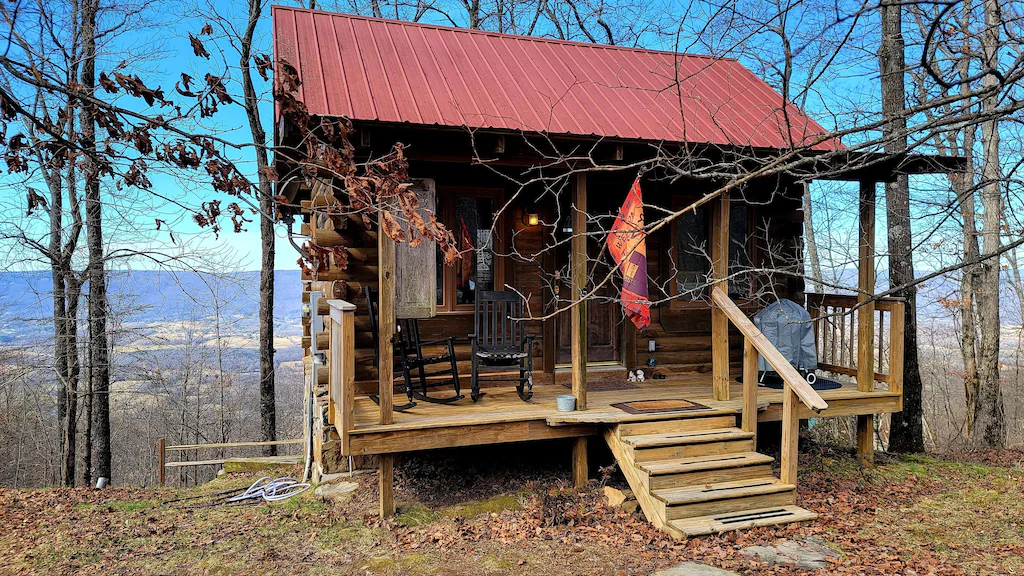 a log cabin with a red tin roof and a great porch, a fantastic view for glamping in tennessee