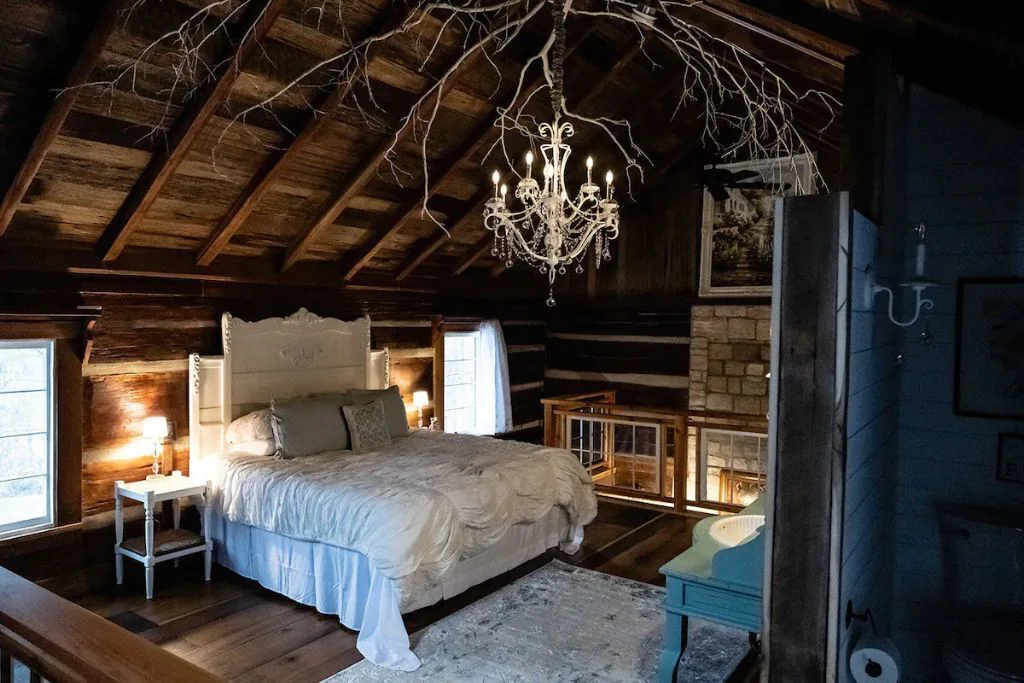 inside bedroom of cabin. chandelier hanging from middle of the ceiling 