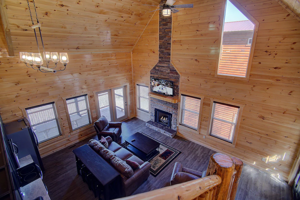 photo from stairs of cabin, fireplace and furniture below