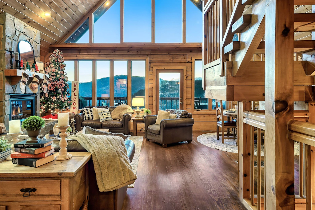 photo in living space of cabin, stairs on the rights and couches and fireplace on the left 