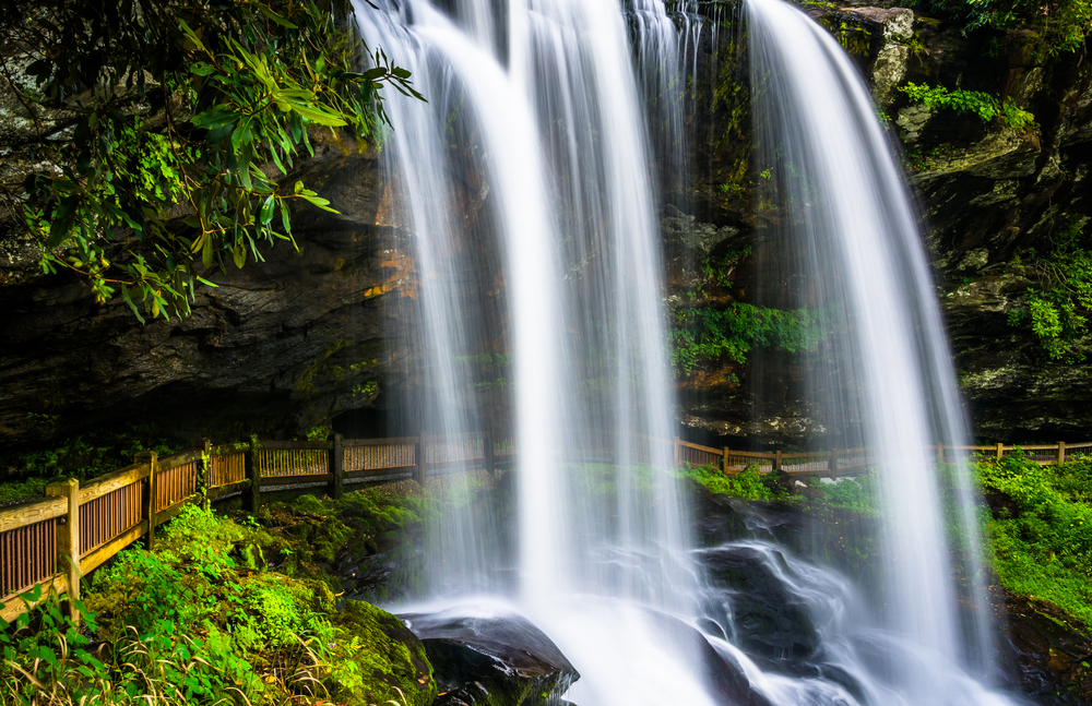 waterfall near Franklin, NC known as dry falls, cascading down from above with a walkway behind it