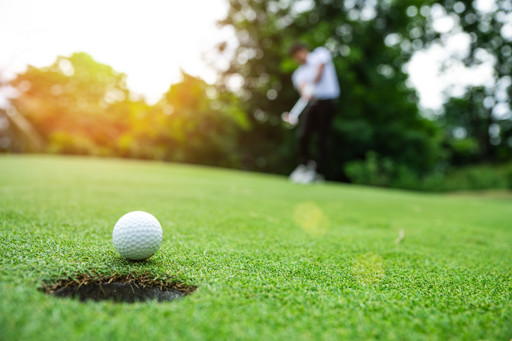 Golf ball going into the hole at sunset