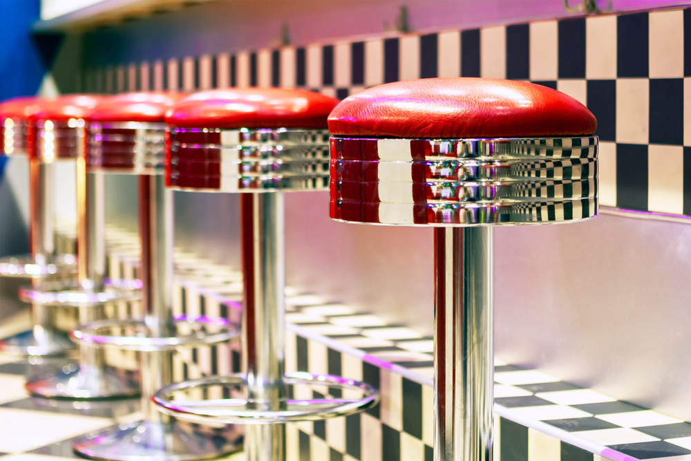 red metal stools line up at a checkered bar at the motor company grill